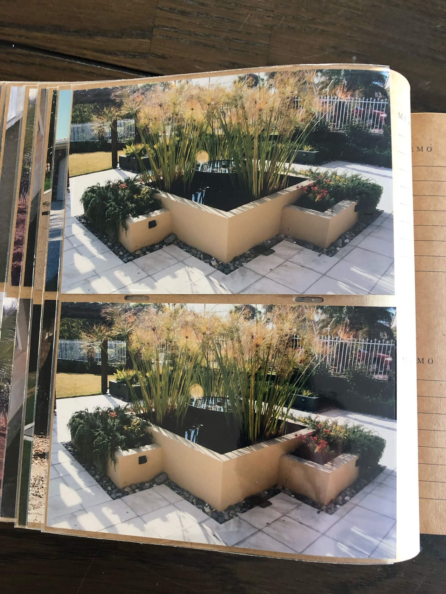 Two identical photographs side by side show a modern outdoor patio garden. The garden features cube-shaped planters with tall, grass-like plants and smaller flowers. The area is paved, and a metal fence encloses the peaceful space.